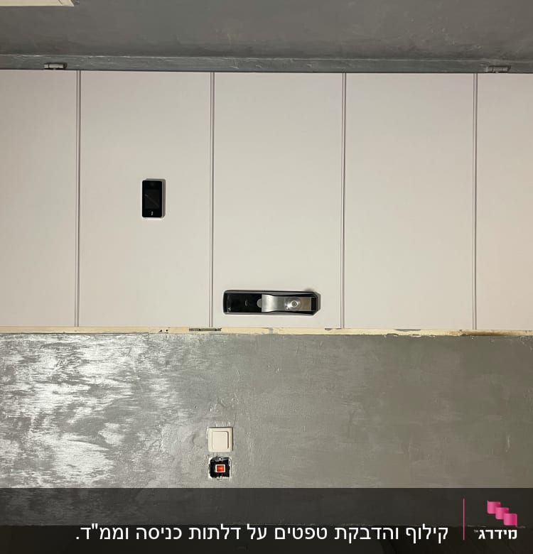 דלת לבנה עם ידית כסופה על קיר אפור